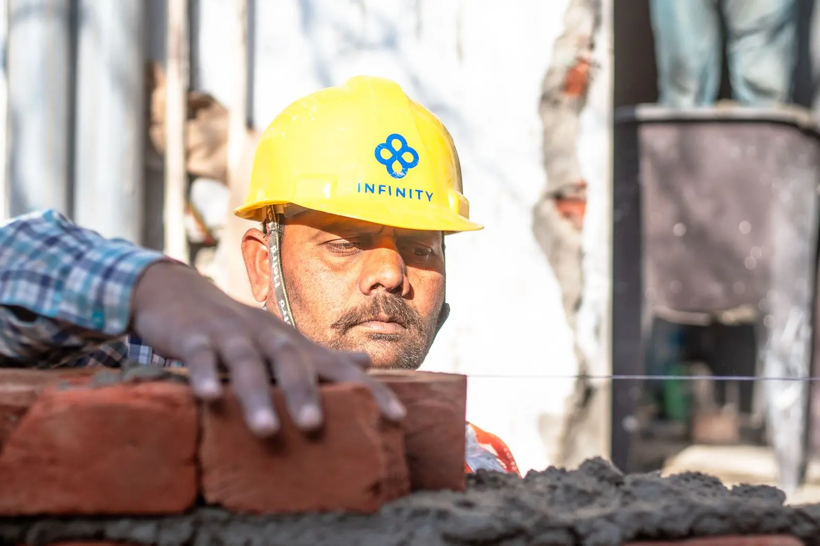 Mason aligning bricks on a wall — representative renovation and civil work reference